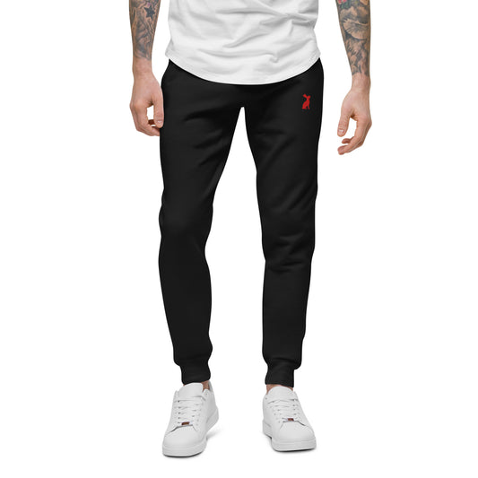 Modelo masculino con pantalón KÖNE negro unisex y camiseta beige, corte recto y cómodo.