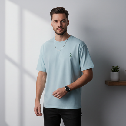 Hombre con camiseta KÖNE celeste, logo verde bordado, estilo casual y corte estructurado.
