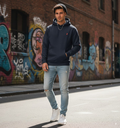  Hombre con sudadera azul marino KÖNE y pantalón tejano, estilo urbano casual en interior moderno.