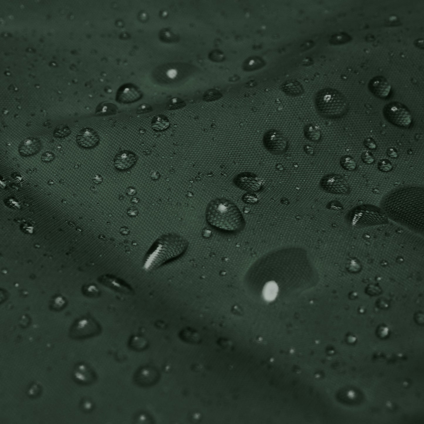 Detalle del tejido impermeable del cortavientos KÖNE verde oscuro con gotas de agua.