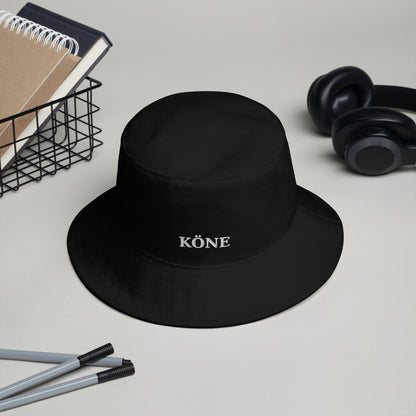 Gorro bucket KÖNE negro de algodón con logo bordado sobre un escritorio